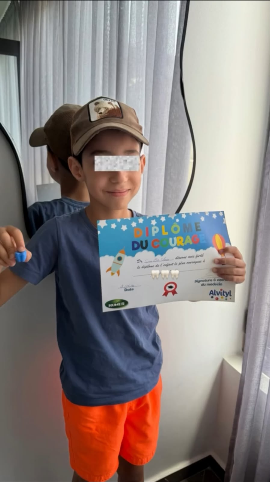 Jeune patient avec son diplôme de bonne conduite dentaire